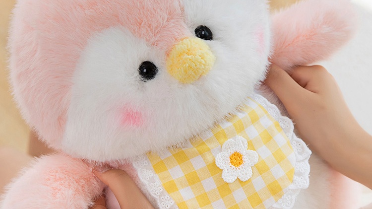 Holding a pink and white penguin plush doll wearing yellow plaid clothes