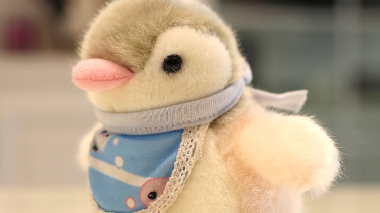 Graue und weiße Pinguin-Plüschpuppe mit blauem Patchwork-Lätzchen