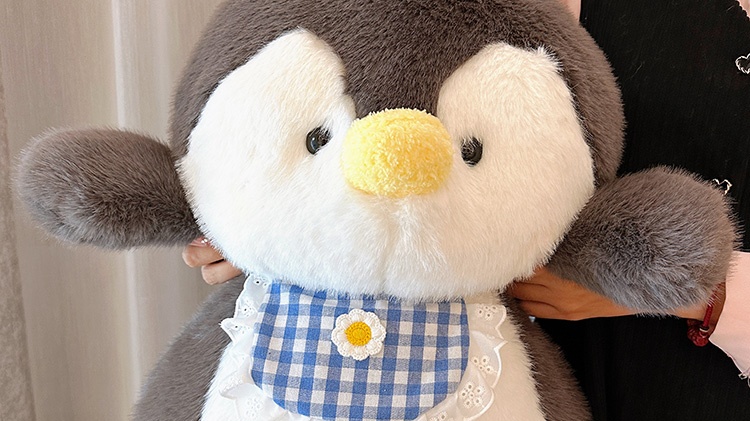 Penguin plush doll wearing blue plaid bib