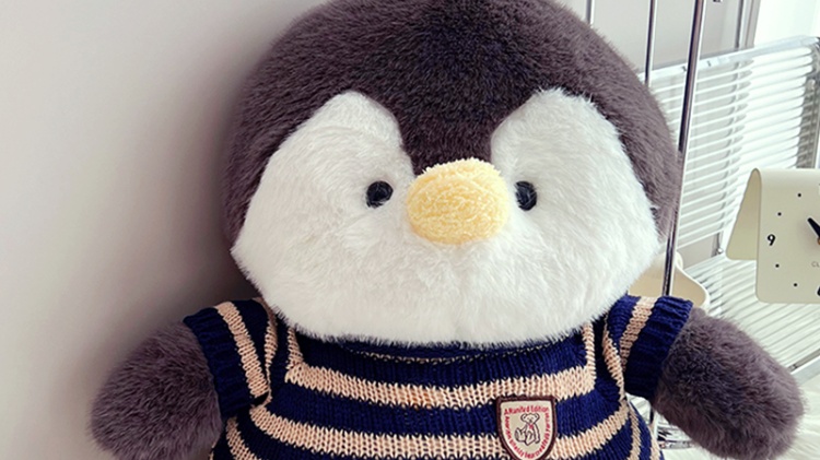 Penguin plush doll wearing knitted sweater