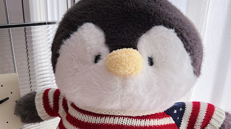 Penguin plush doll wearing red knitted sweater